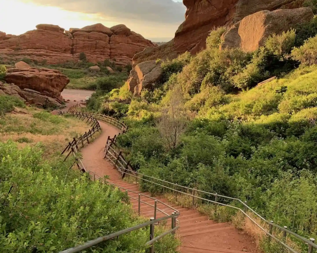 Red rocks amphitheatre pathway surrounded by red sandstone formations and green summer landscape.