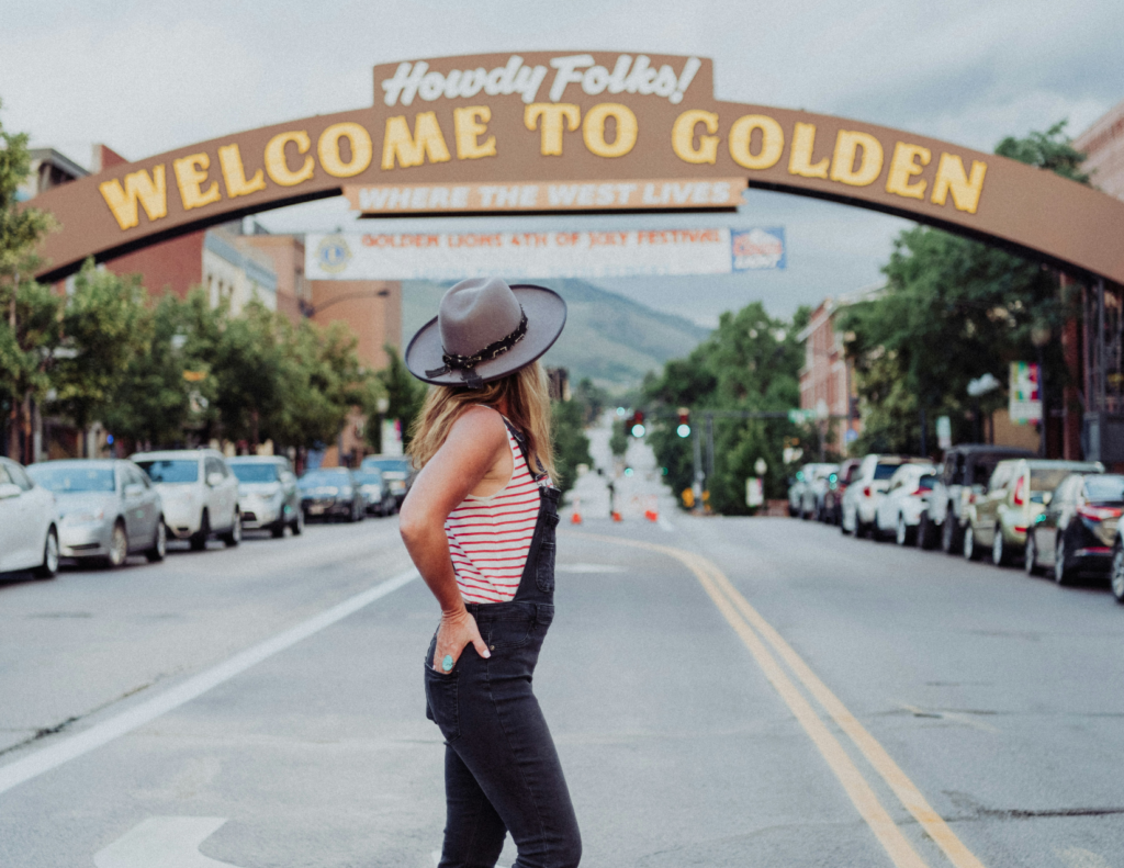 Best Colorado Towns For A Relaxing Colorado Weekend Trip 1 Person standing beneath the welcome to golden sign on a downtown street in golden, colorado on their colorado weekend trip
