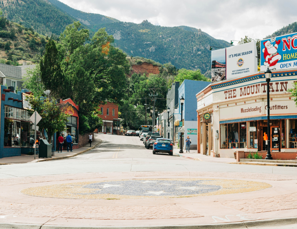 Best Colorado Towns For A Relaxing Colorado Weekend Trip 5 Downtown manitou springs street with colorful storefronts and mountains in the background.