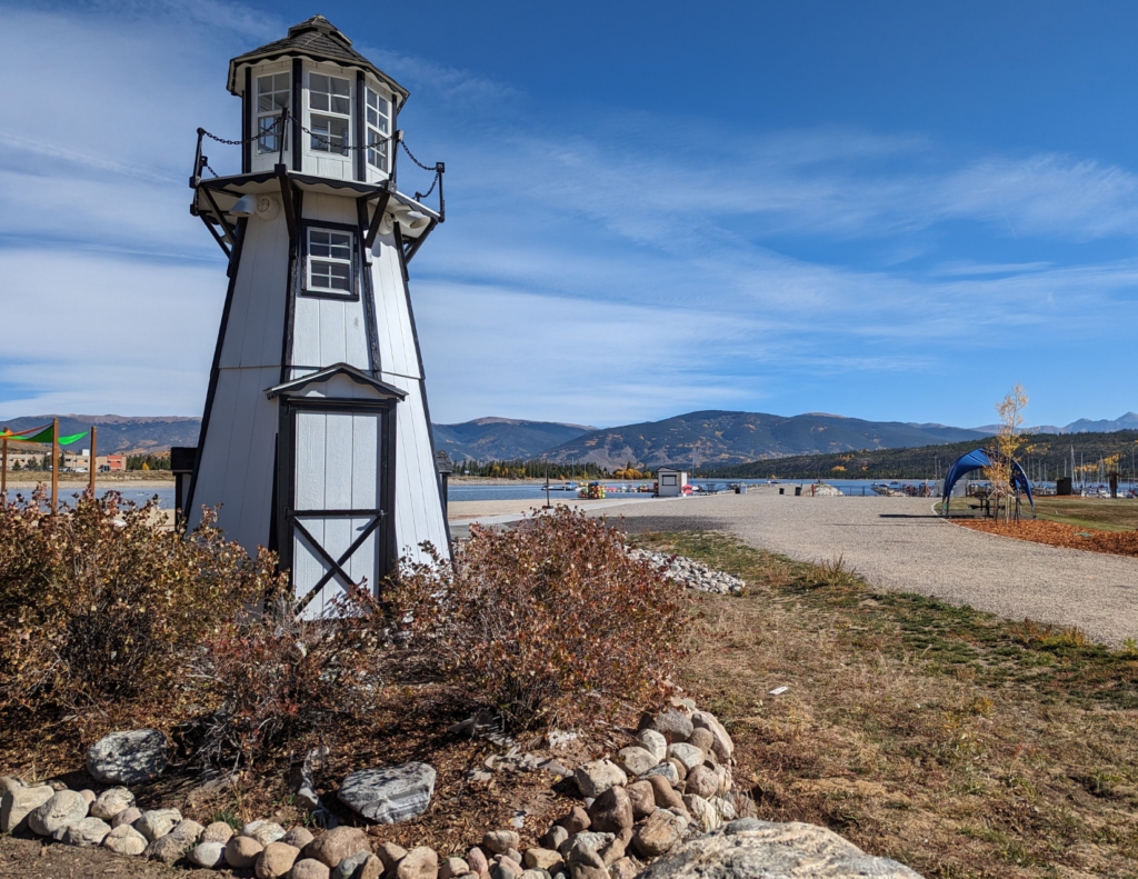 Best Colorado Towns For A Relaxing Colorado Weekend Trip 7 Small lighthouse near a colorado mountain lake with marina views and mountains in the distance.